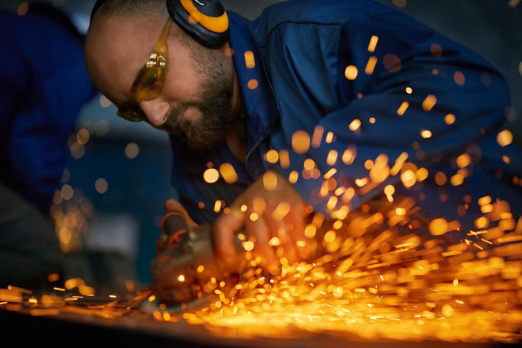 man-working-with-electric-steel-cutter-machine-near-sparks