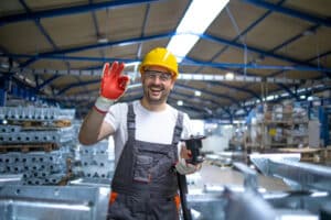 portrait-of-factory-worker-in-protective-equipment-holding-thumbs-up-in-production-hall